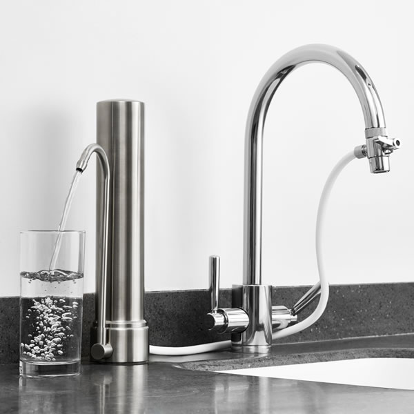 Un verre se remplit d’eau filtrée au robinet d’un purificateur Doulton® posé sur l’évier